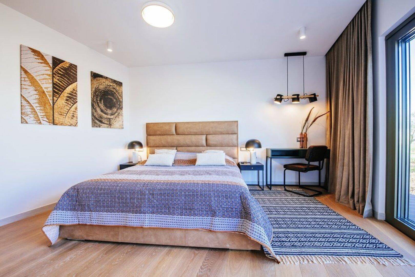 Geräumiges Schlafzimmer mit Holzboden, großem Bett und Zugang zur Terrasse.