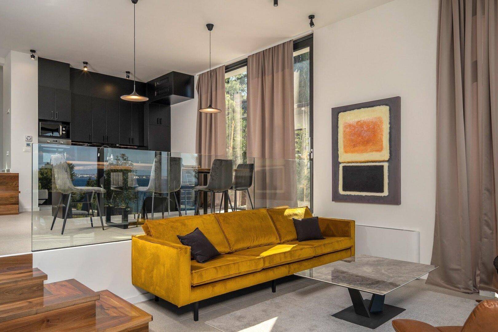 Gemütliche Sitzecke mit gelbem Sofa und Essbereich im Hintergrund, offen gestaltet.