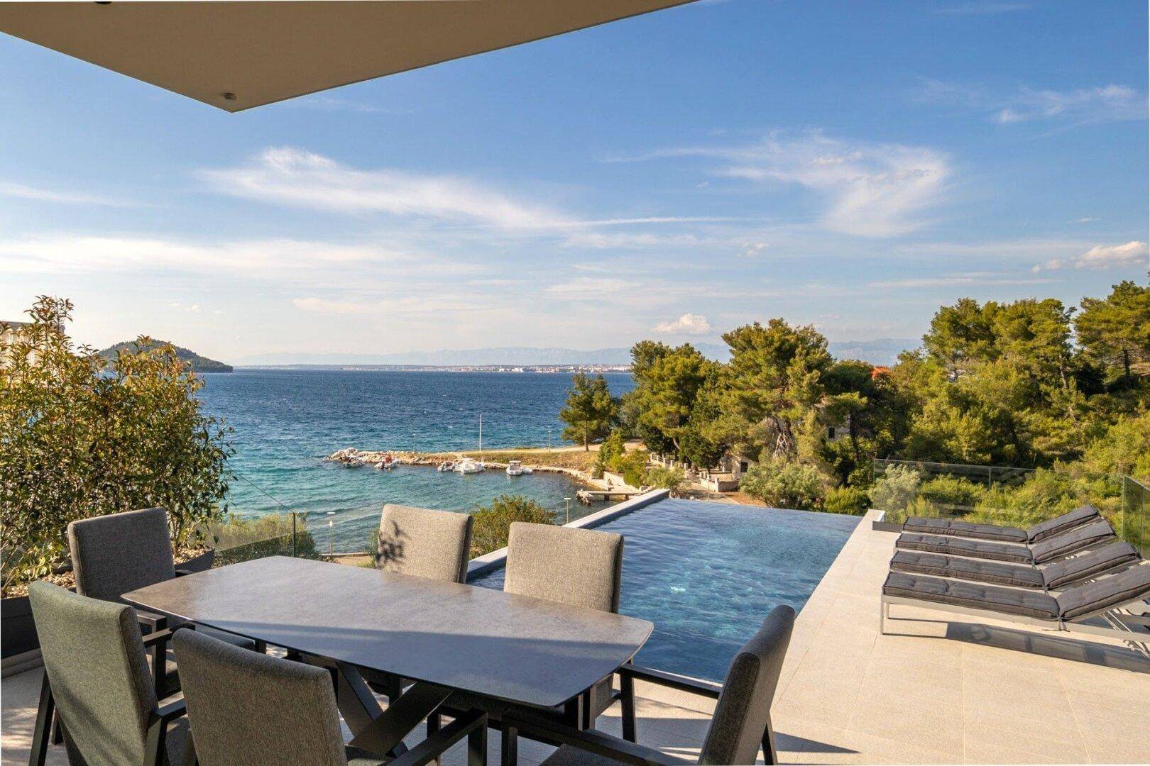 Essbereich im Freien auf der Terrasse mit Meerblick und angrenzendem Pool.