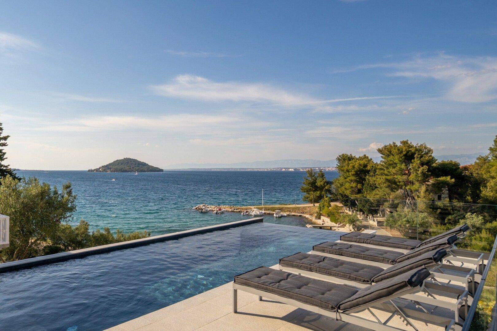 Infinity-Pool mit atemberaubendem Meerblick und bequemen Sonnenliegen.