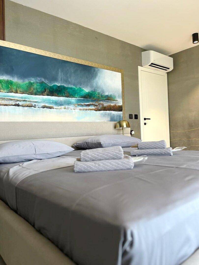 Schlafzimmer mit großem Bett, abstraktem Kunstwerk und Klimaanlage für angenehme Nächte.