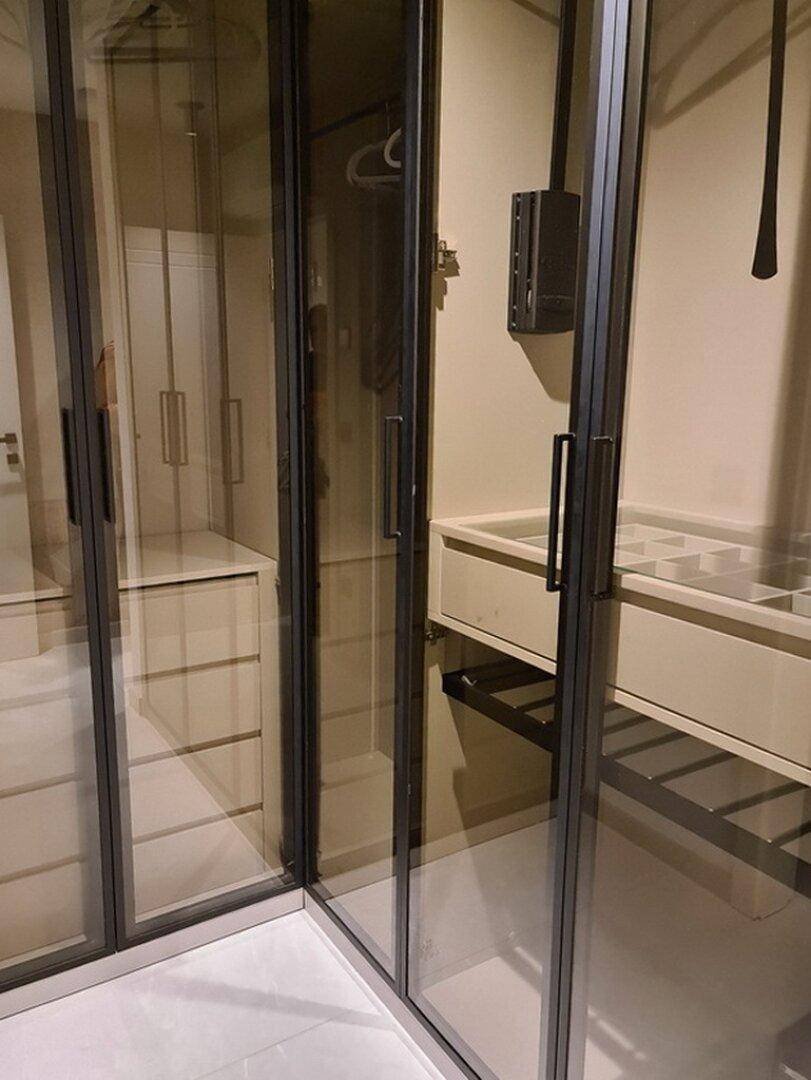 Begehbarer Kleiderschrank mit viel Stauraum, eleganten Glastüren und integrierten Regalen.
