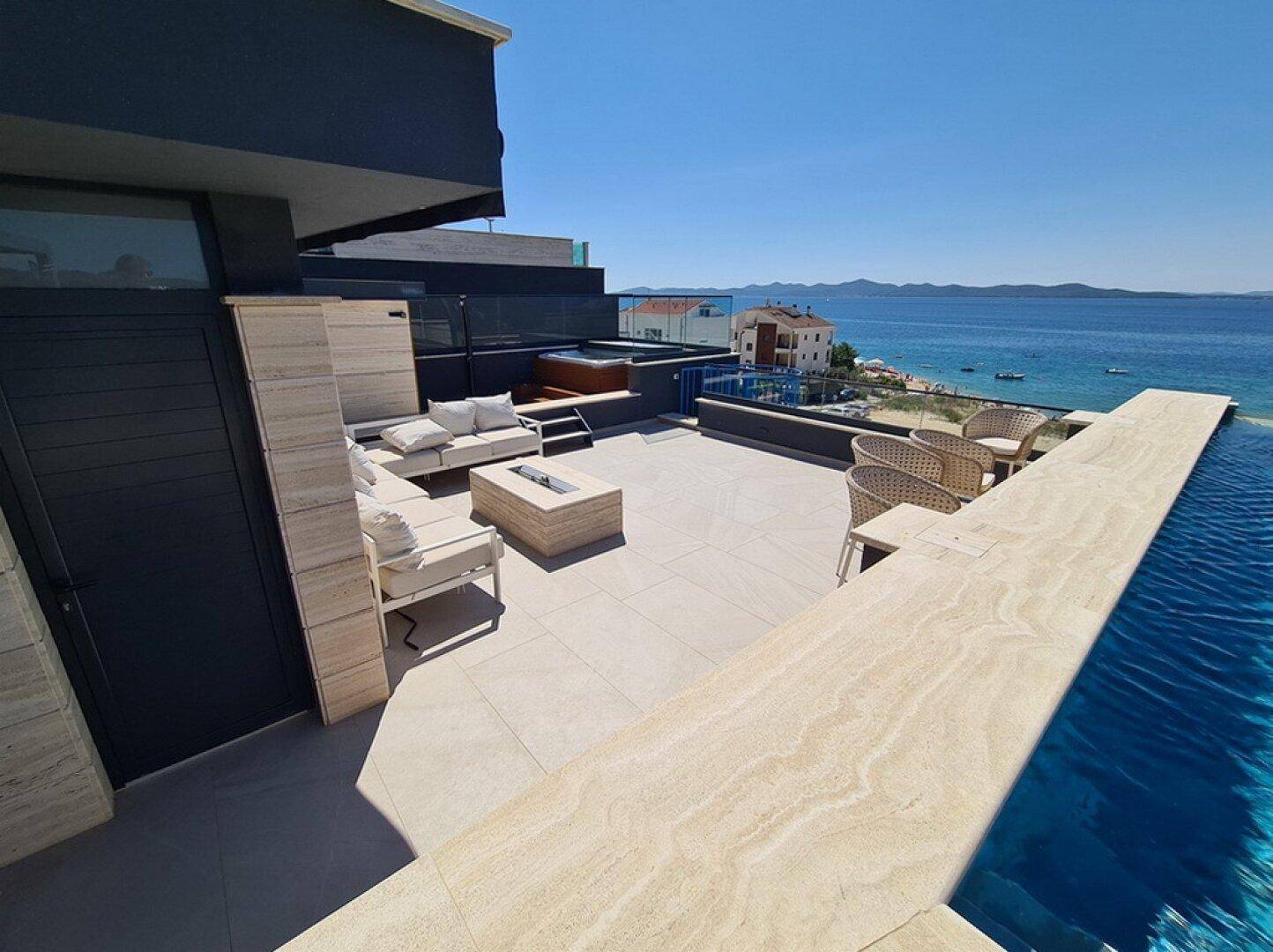 Luxuriöse Dachterrasse mit Infinity-Pool, Lounge-Möbeln und atemberaubendem Meerblick.