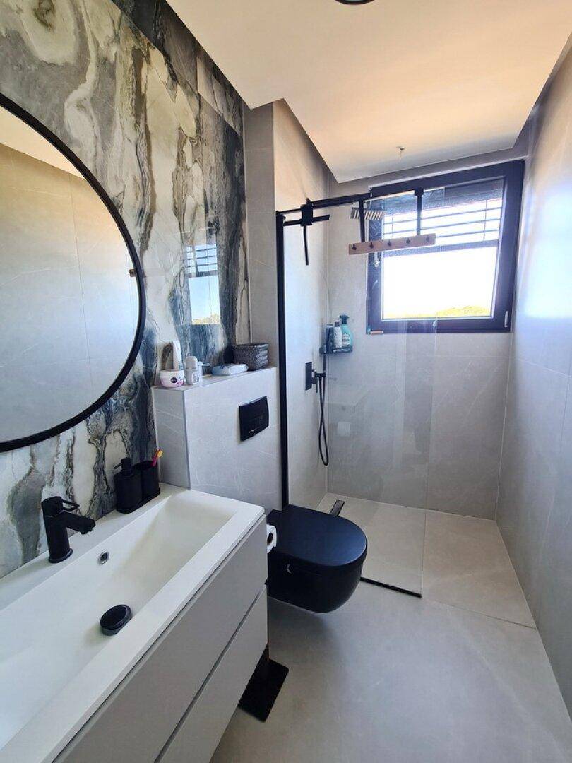 Modernes Badezimmer mit begehbarer Dusche, Wand-WC und stilvollen Fliesen an den Wänden.