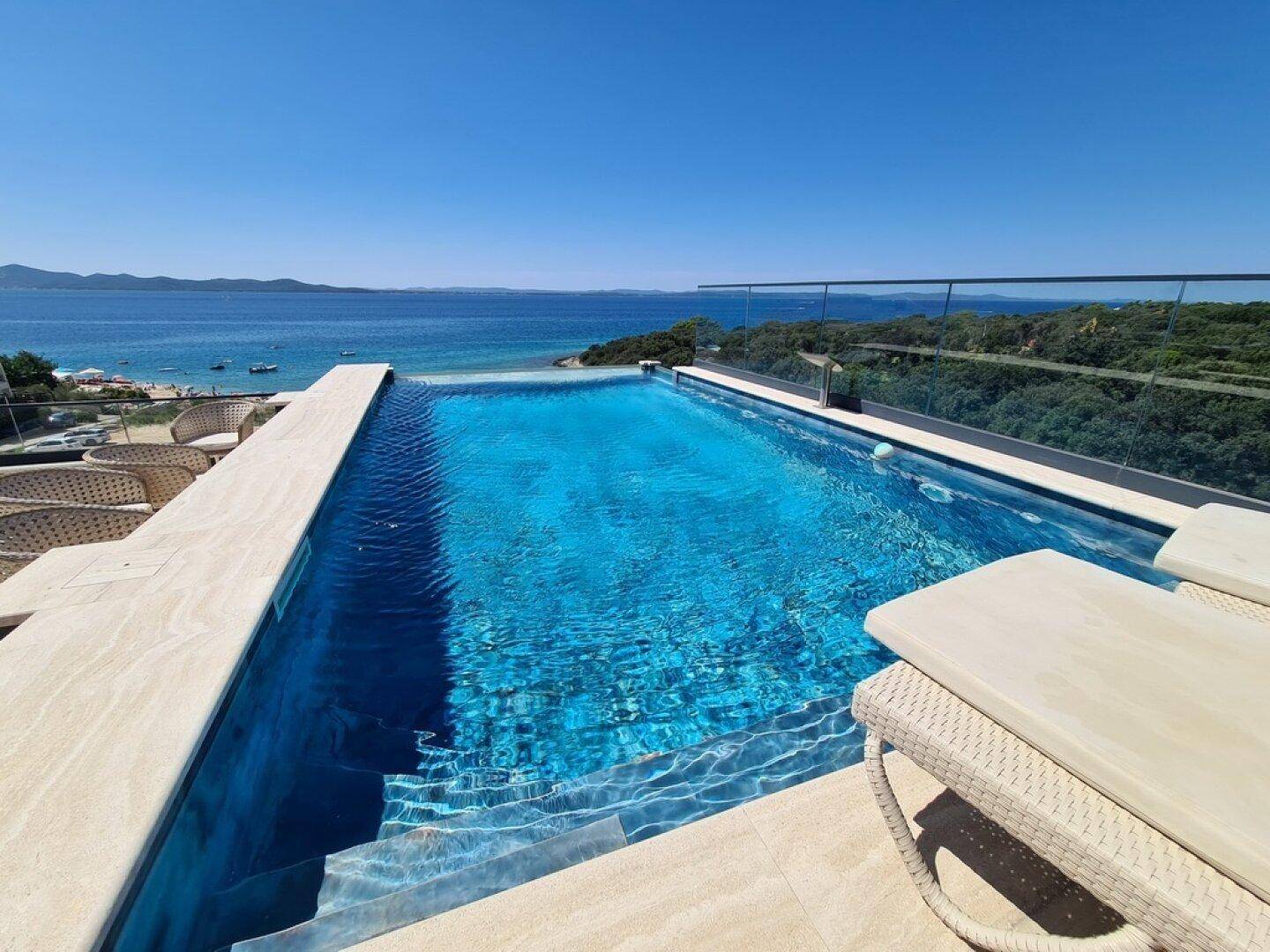 Luxuriöser Infinity-Pool mit atemberaubendem Meerblick und bequemen Sonnenliegen am Horizont.