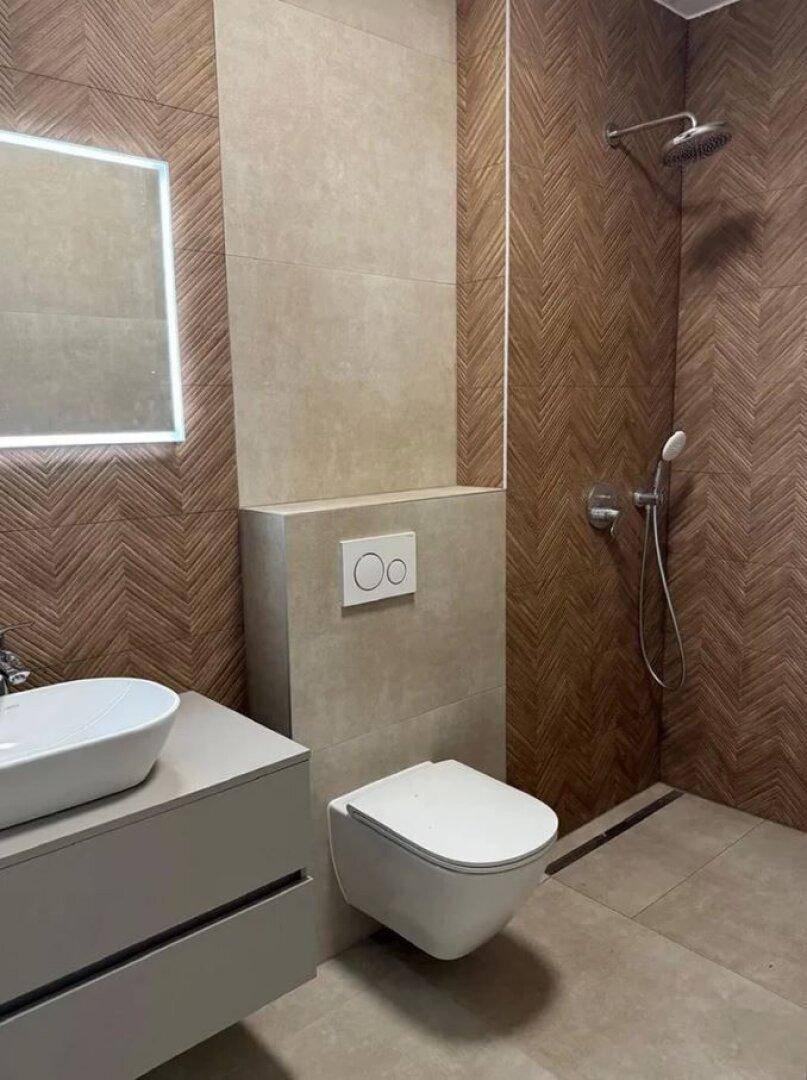 Modernes Badezimmer mit Wand-WC, Einzelwaschbecken, Regendusche und stilvollen Fliesen.