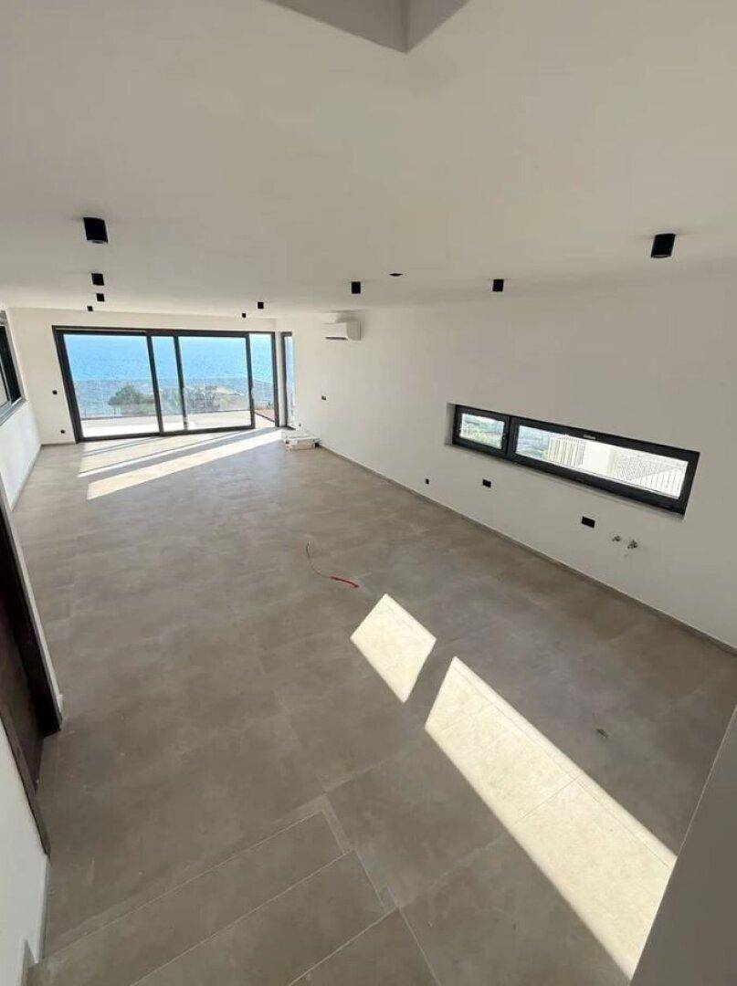 Helles Wohnzimmer mit Fliesenboden, großen Fenstern und weitem Blick auf das Meer und die Landschaft.