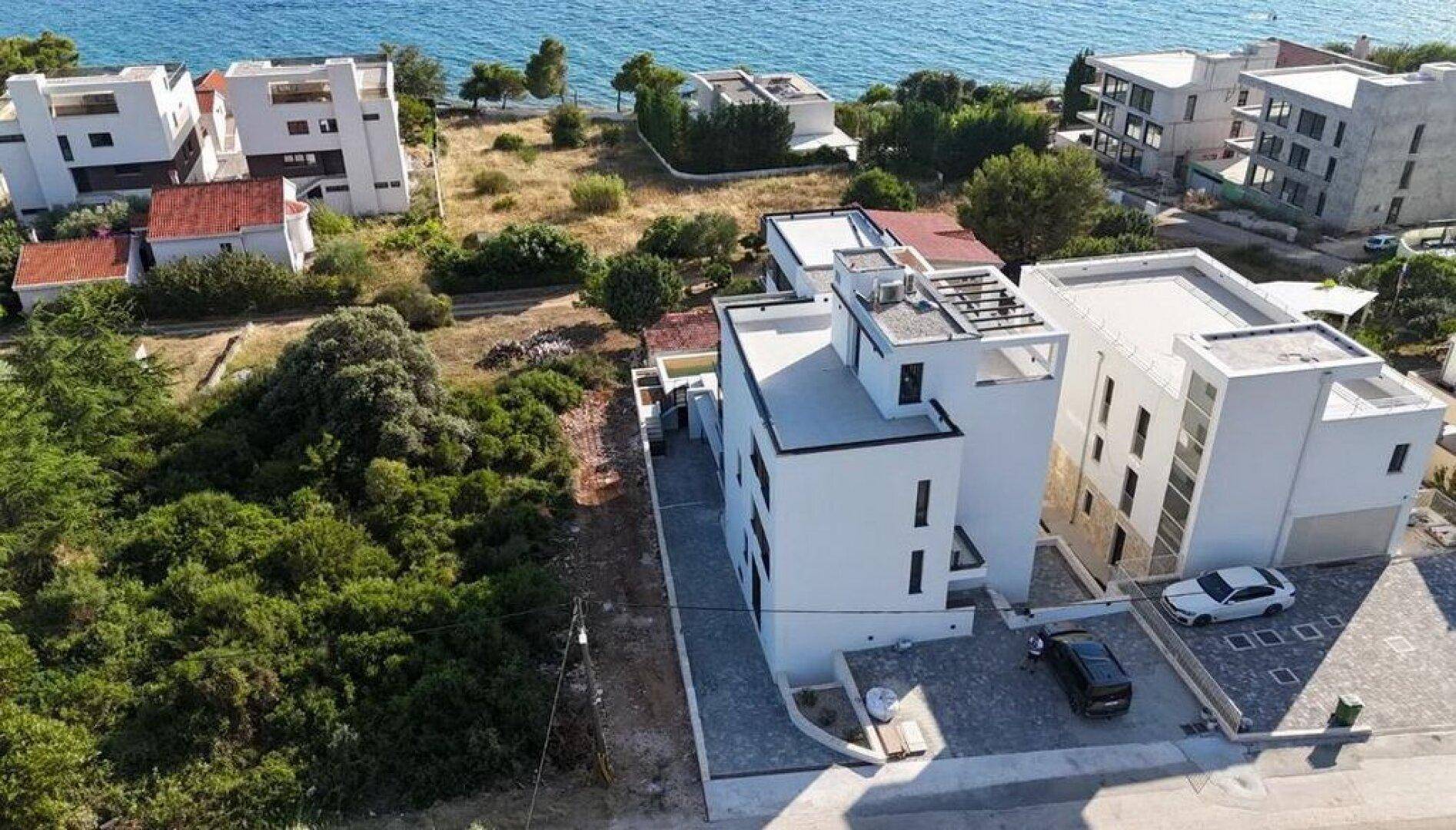 Luftaufnahme der modernen Wohnanlage mit Meerblick und umliegenden Gebäuden.