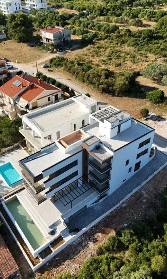 Moderne Wohnanlage mit Pools und Terrassen, umgeben von grünen Hügeln.