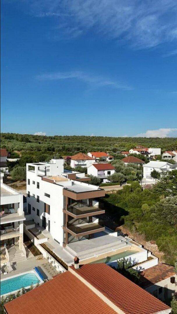 Moderne Wohnanlage mit Pools und Terrassen, umgeben von mediterraner Vegetation.