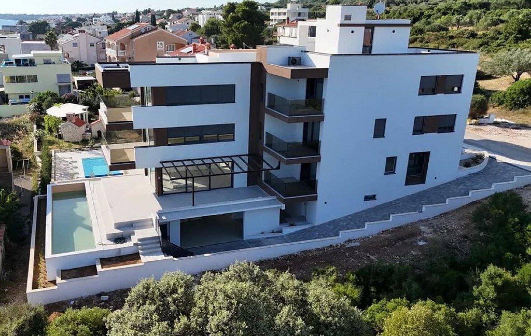 Neubau-Wohnanlage mit moderner Architektur, Pools und umliegender Natur.