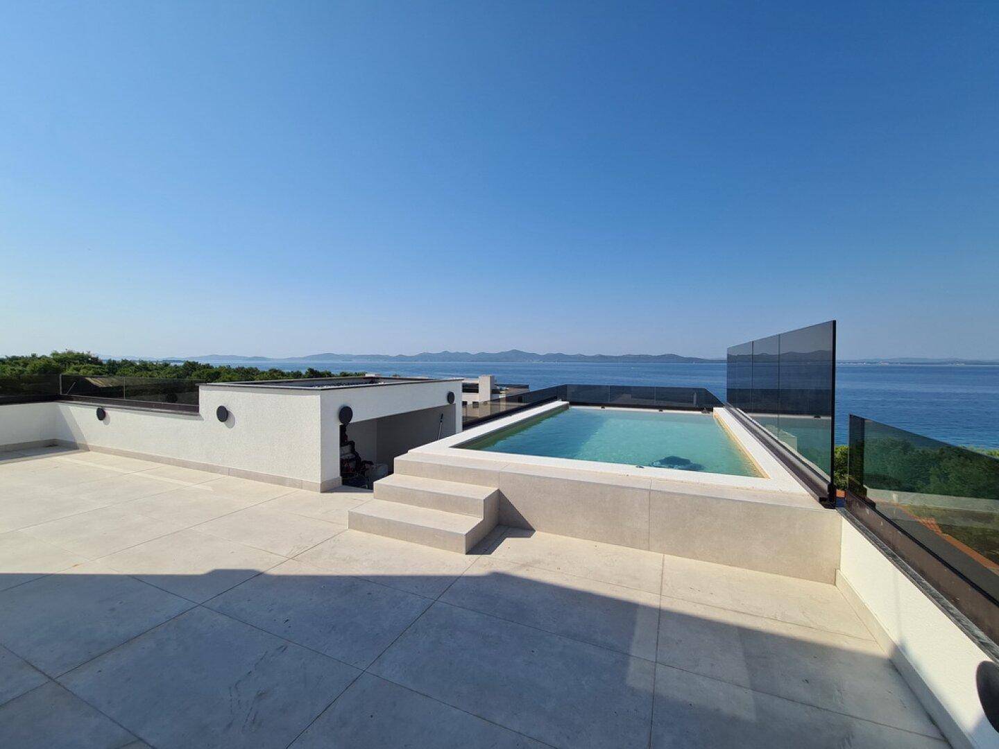 Geräumige Dachterrasse mit Pool und weitem Panoramablick auf das Meer und die Küste.