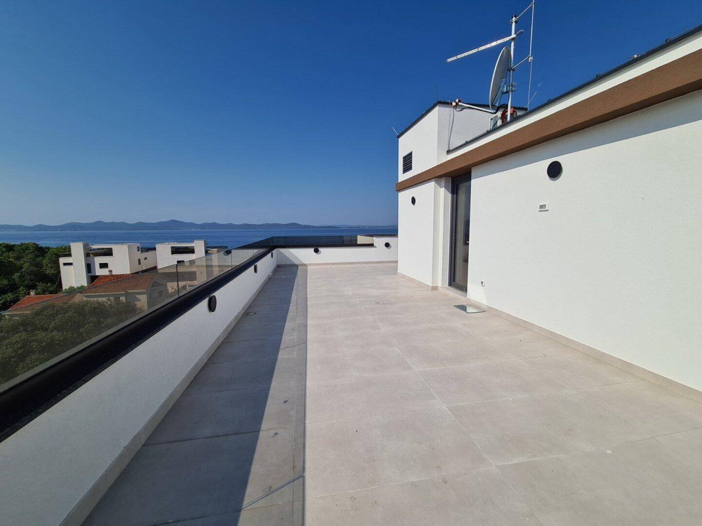 Dachterrasse mit Meerblick und moderner Glasbrüstung, ideal für Entspannung im Freien.