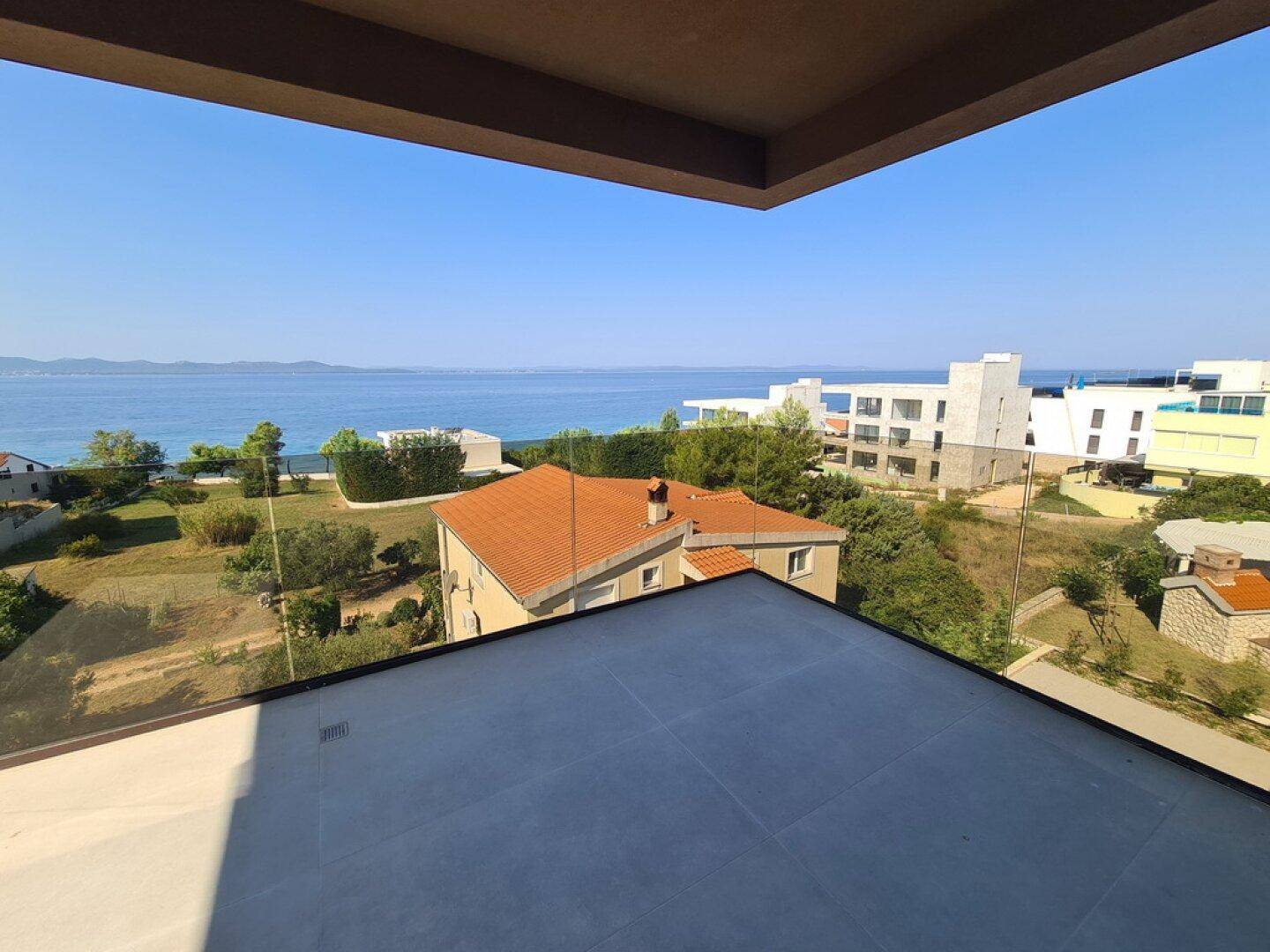 Balkon mit Glasbrüstung und Panoramablick auf das Meer und die umliegenden Gebäude.