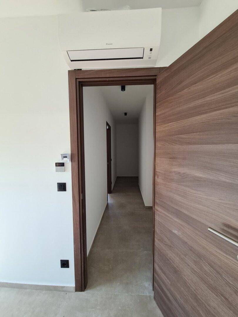 Moderner Eingangsbereich mit Holztür und Klimaanlage für angenehmes Raumklima.
