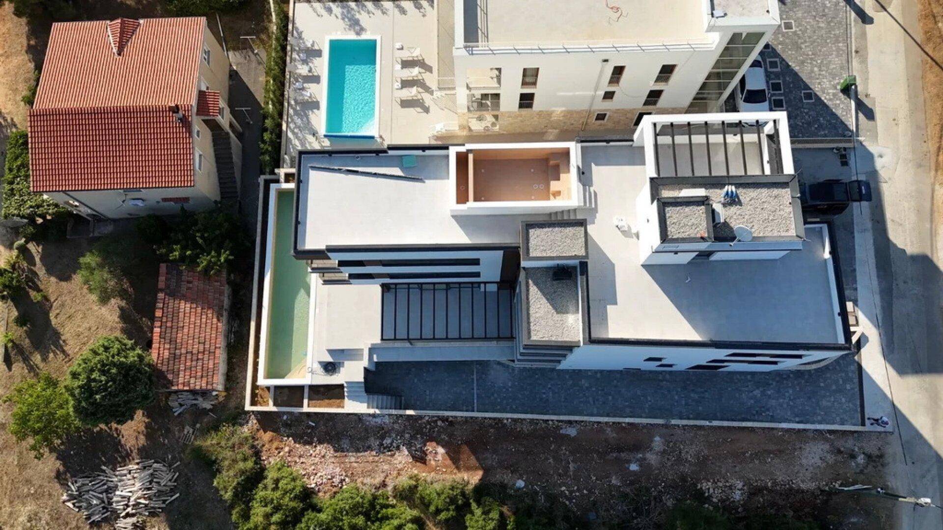 Detaillierte Luftaufnahme der modernen Architektur des Gebäudes mit Flachdach und Pools.