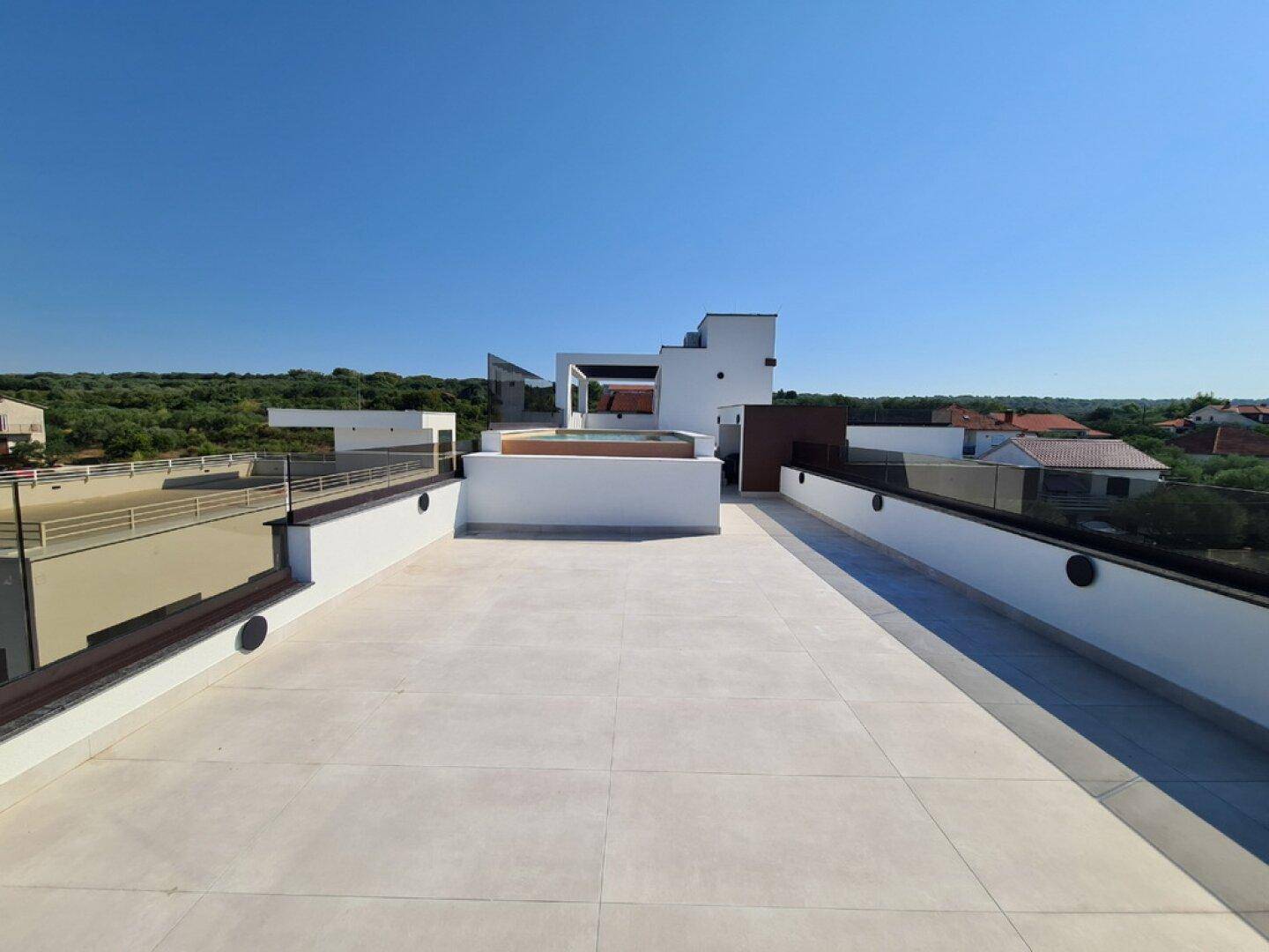 Große, unmöblierte Dachterrasse mit weitem Blick und moderner Architektur im Hintergrund.