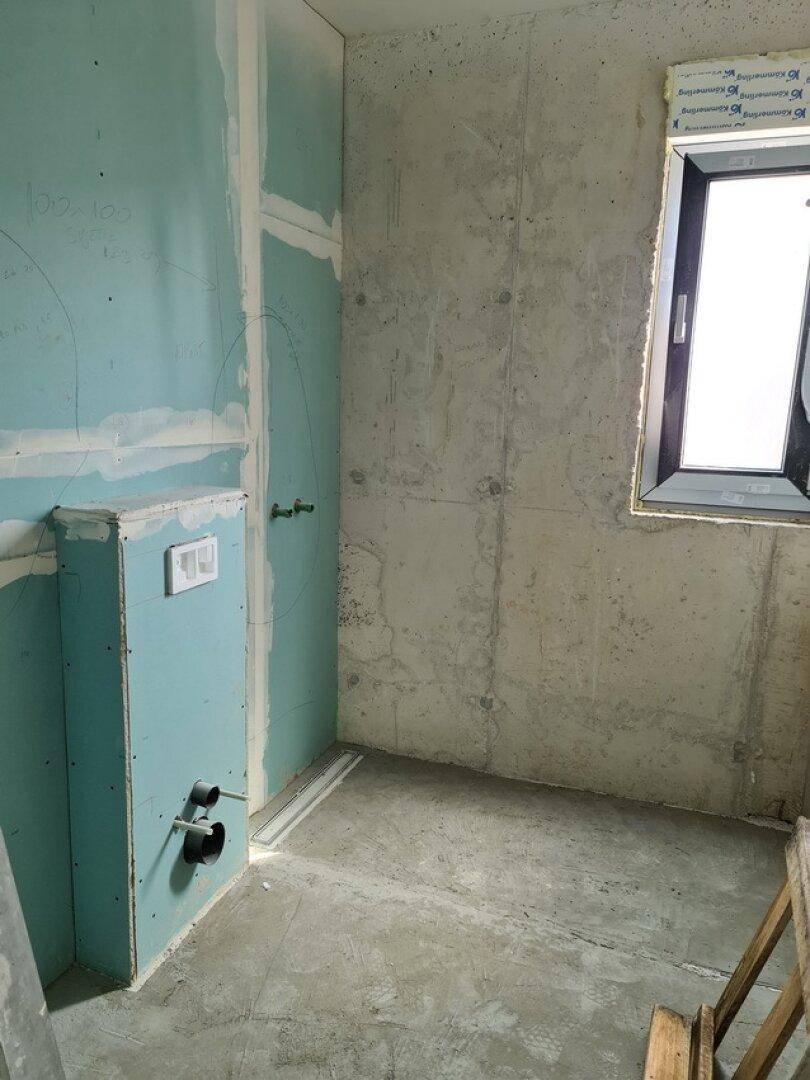 Unfertiges Badezimmer mit Trockenbauwänden und einem Fenster für natürliches Licht.