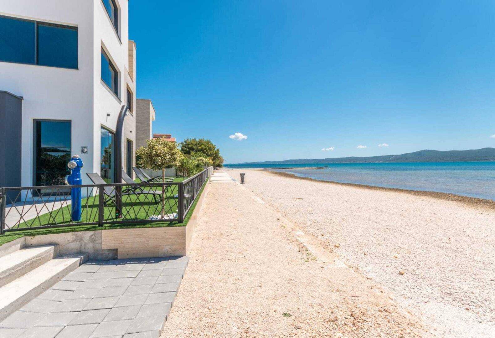 Moderne Gebäude am Strand mit gepflastertem Weg und weitem Blick auf das Meer.