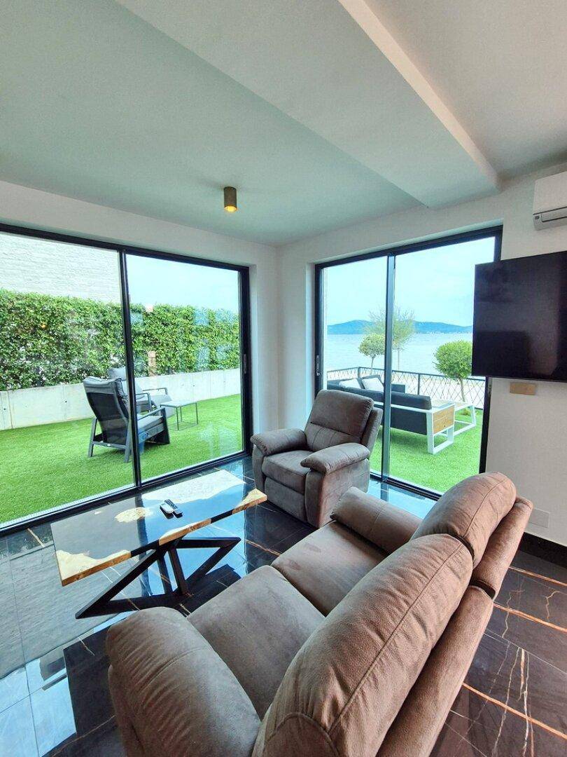 Helles Wohnzimmer mit großen Schiebetüren, die den Blick auf die Terrasse und das Meer freigeben.