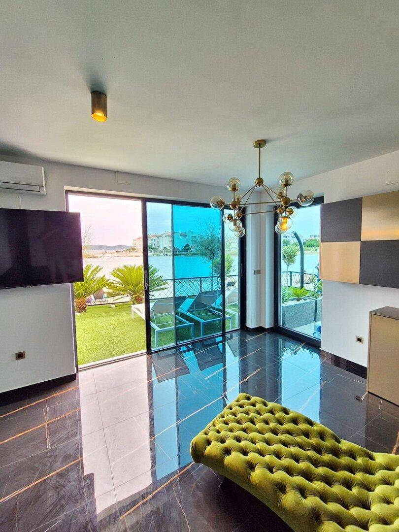 Geräumiges Wohnzimmer mit glänzendem Boden, bequemer Chaiselongue und weitem Meerblick.