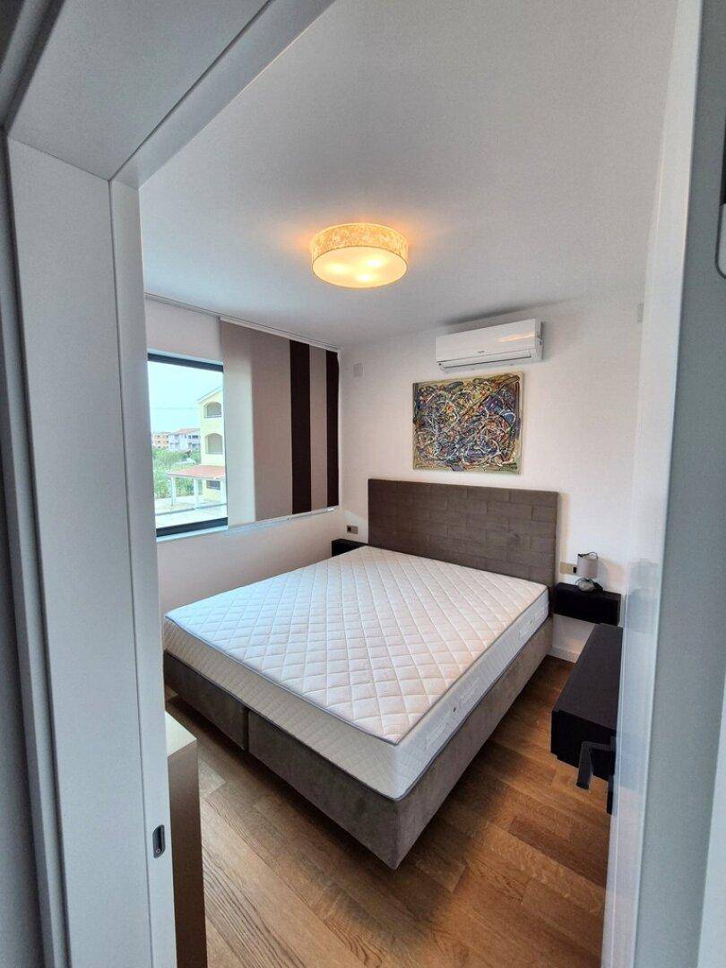 Helles Schlafzimmer mit Holzboden, großem Bett und Fenster mit Blick auf die Umgebung.