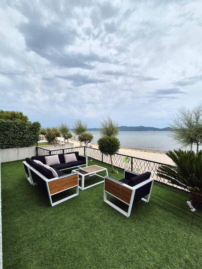 Gemütliche Außenterrasse mit modernen Lounge-Möbeln und direktem Blick auf den Strand und das Meer.
