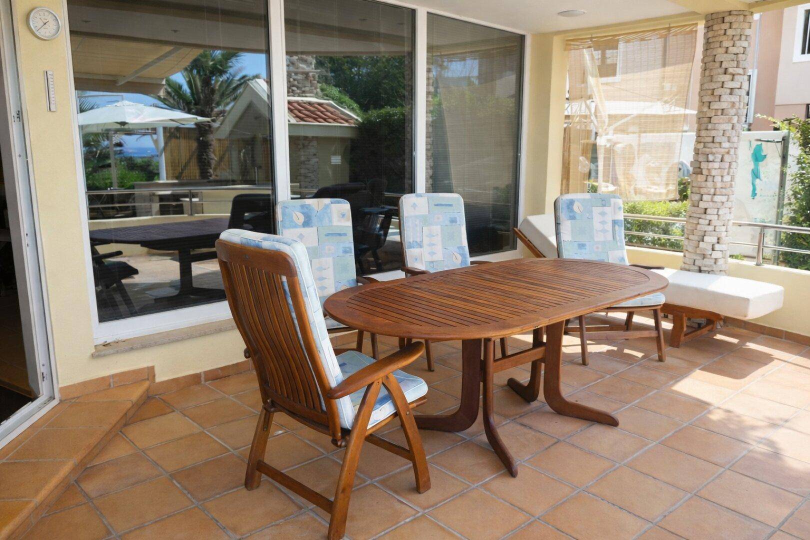 Geräumige Terrasse mit Holztisch, Stühlen und Blick auf die grüne Umgebung.