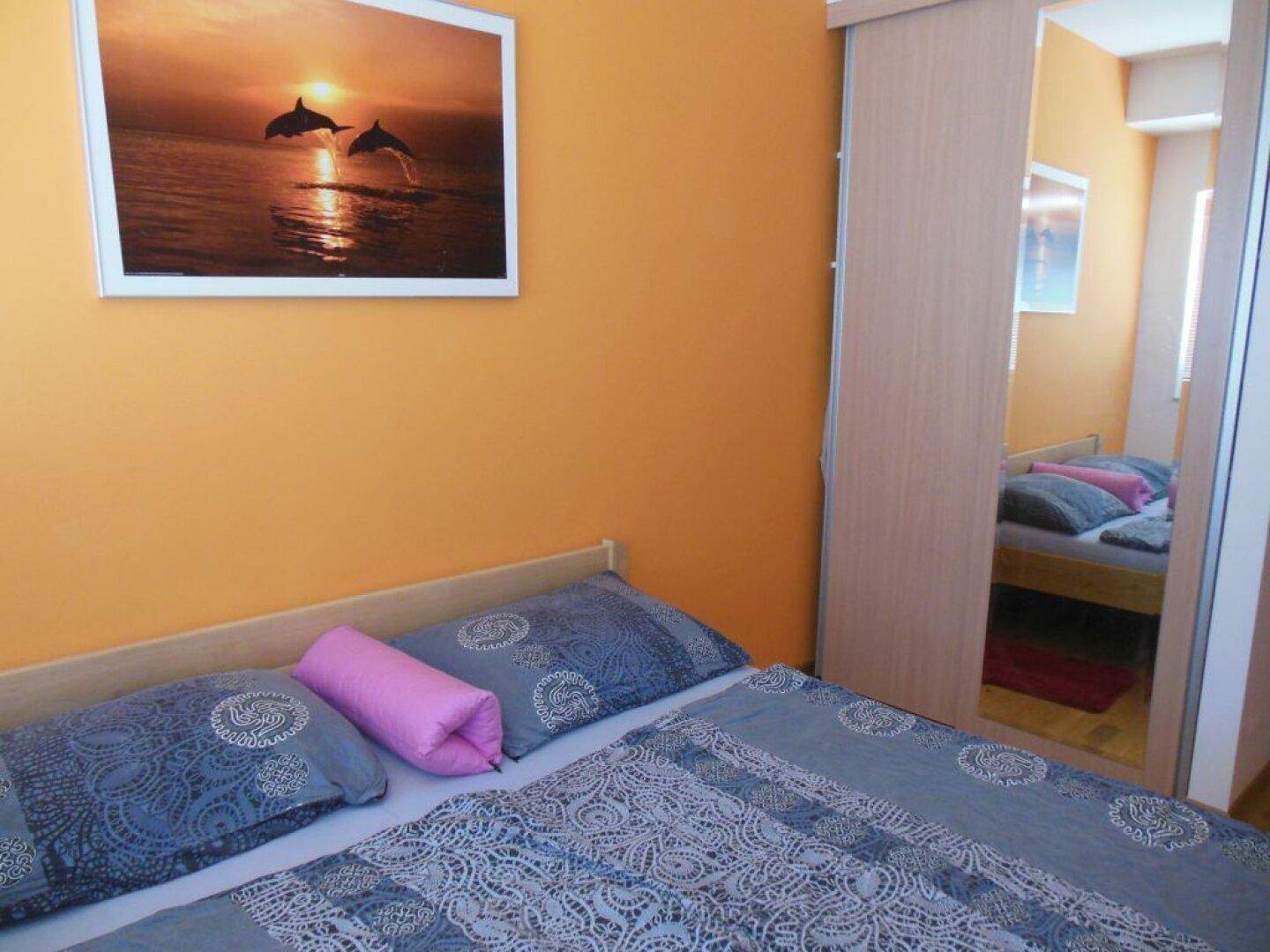 Gemütliches Schlafzimmer mit orangefarbenen Wänden und einem großen Kleiderschrank mit Spiegeltüren.