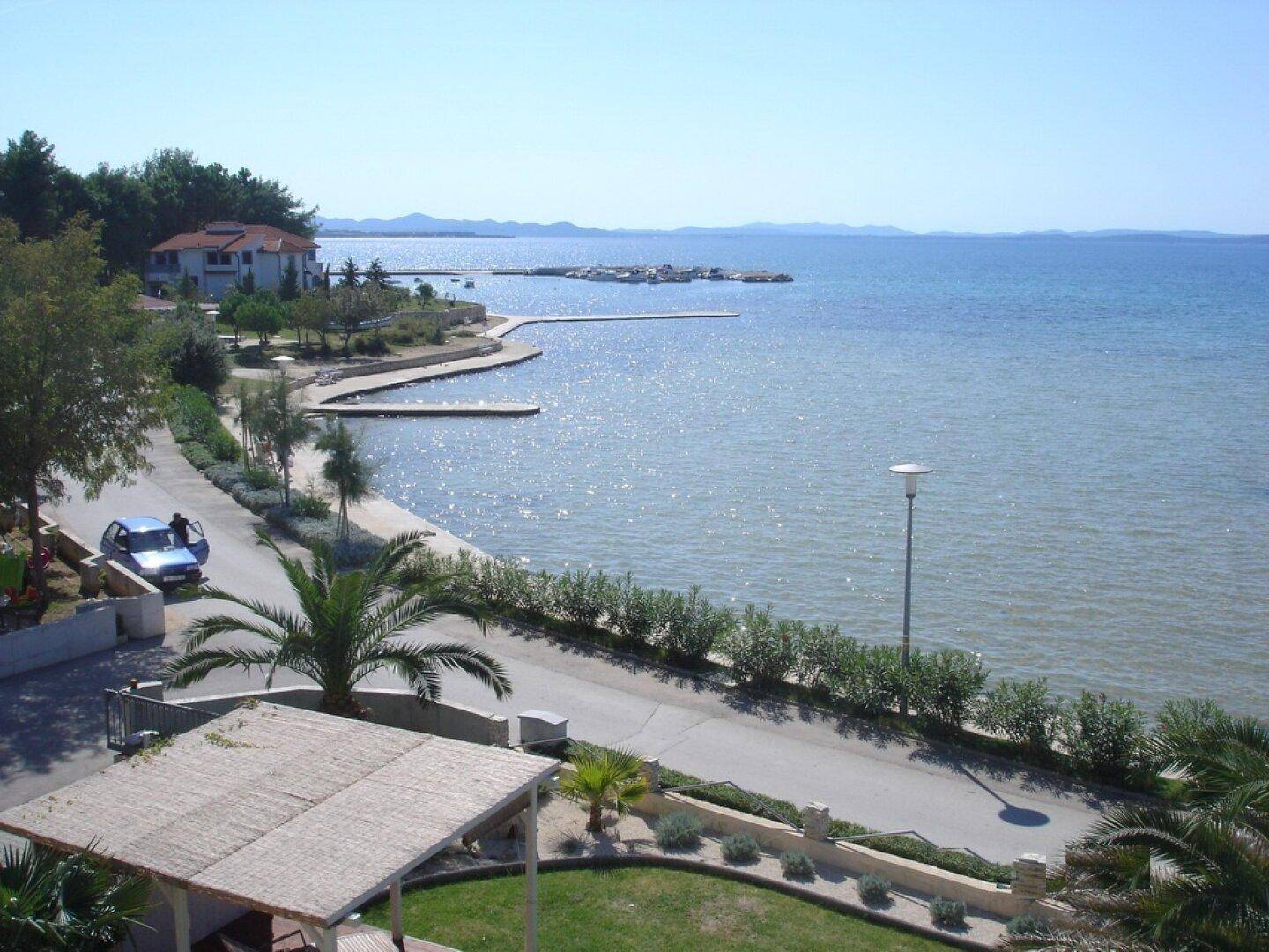 Malerische Küstenstraße mit Blick auf das glitzernde Meer und die umliegende grüne Landschaft.