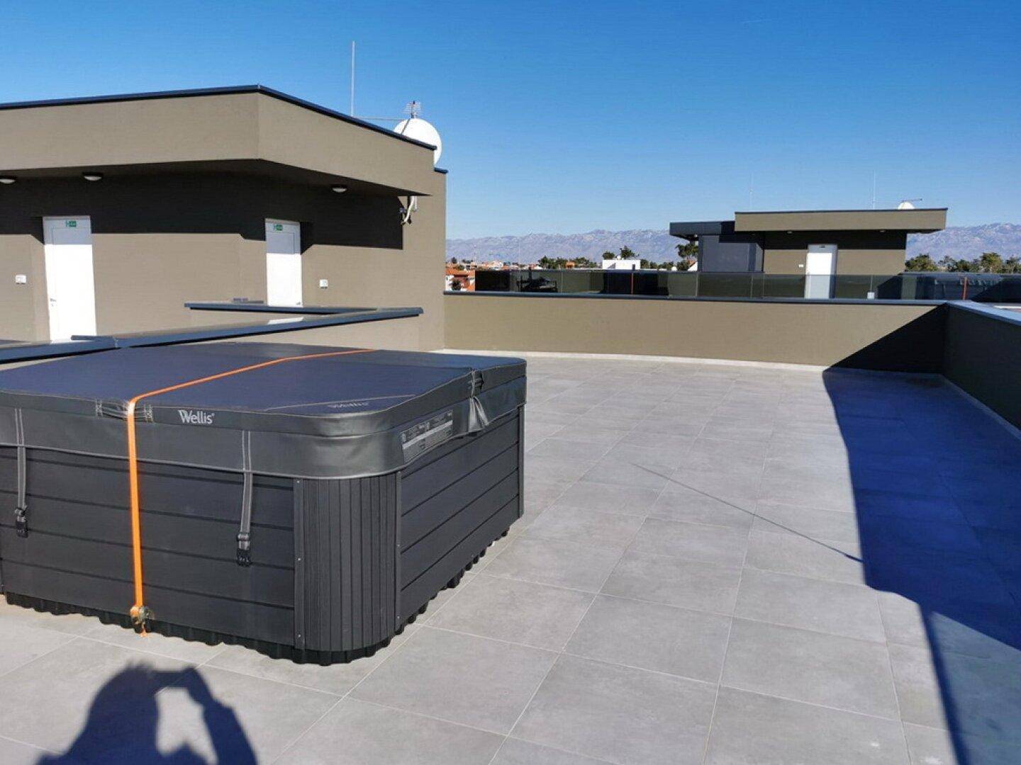 Dachterrasse mit modernem Whirlpool und weitem Blick auf die Umgebung und das Meer.