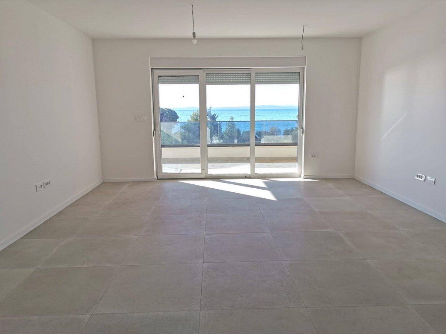 Heller Wohnbereich mit großen Schiebetüren zum Balkon und Blick auf das Meer.