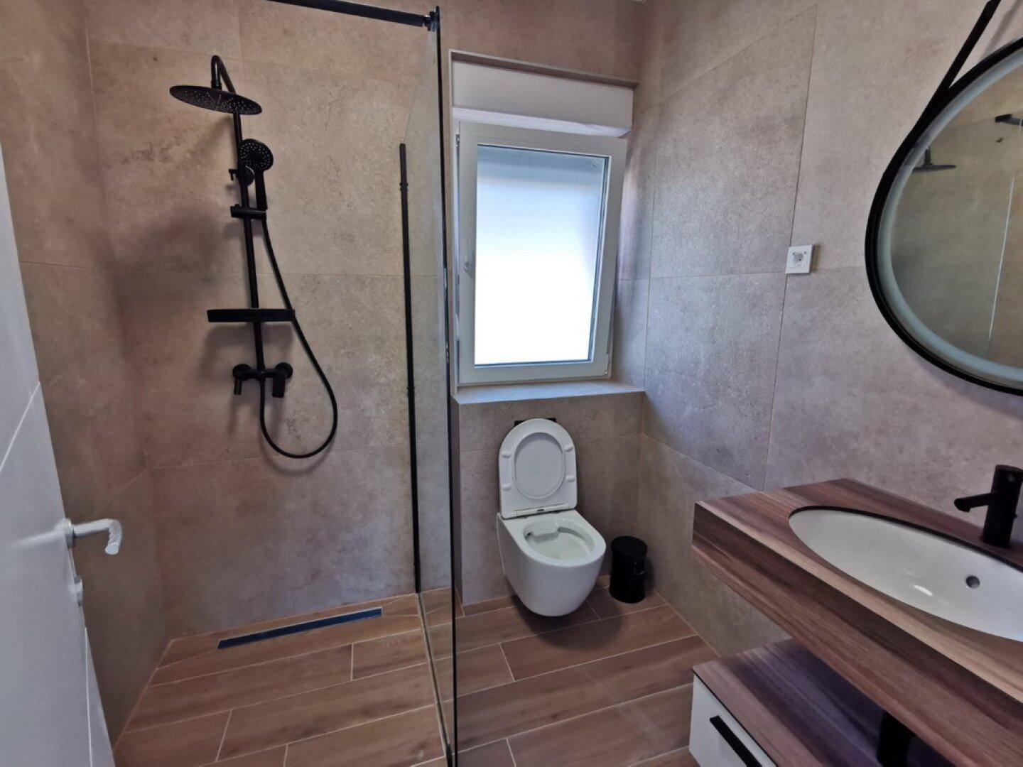 Modernes Badezimmer mit begehbarer Dusche, Wand-WC und Holzwaschtisch, ausgestattet mit Regendusche.