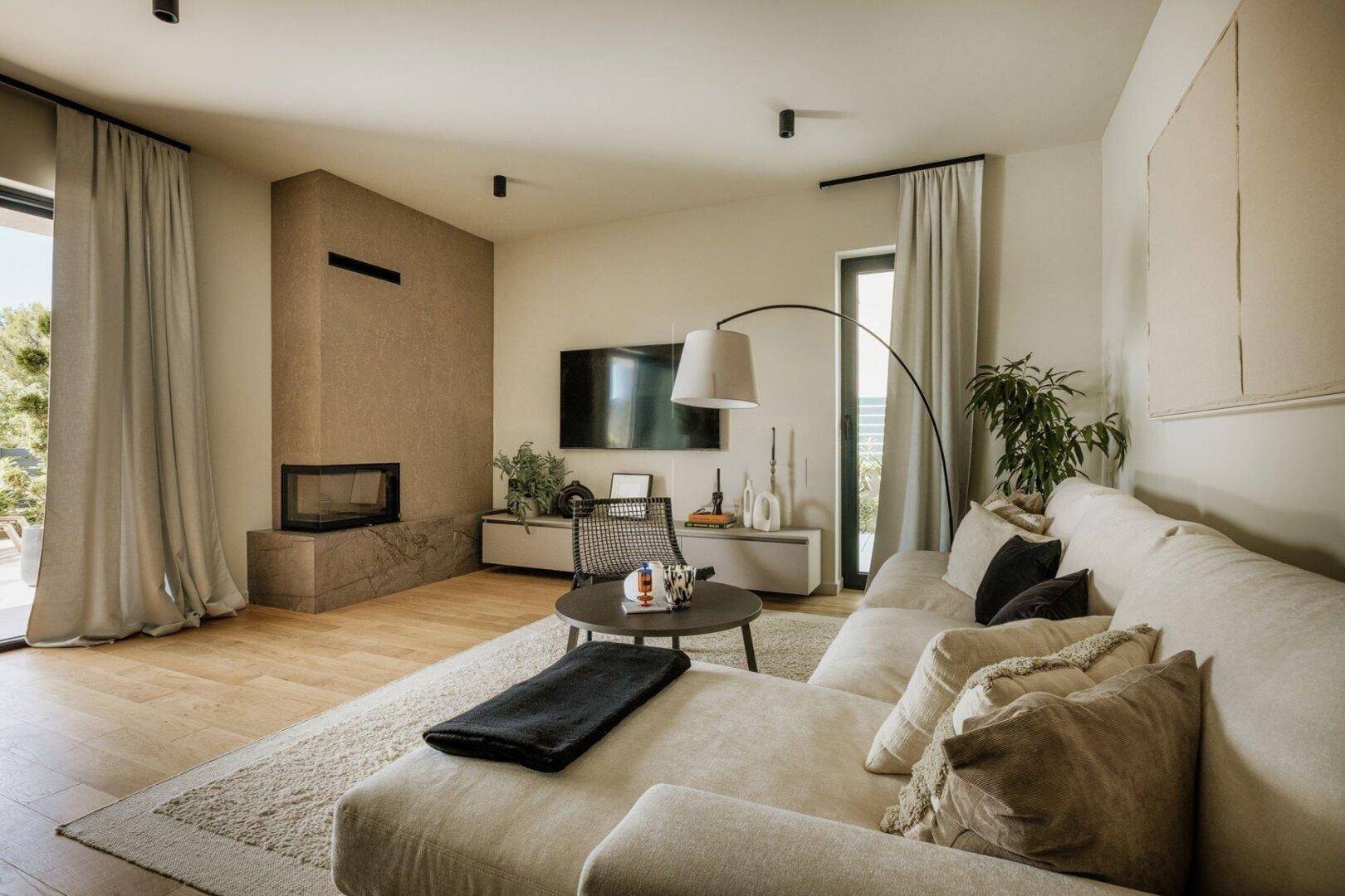 Gemütliches Wohnzimmer mit großem Sofa, Kamin und Zugang zur Terrasse.