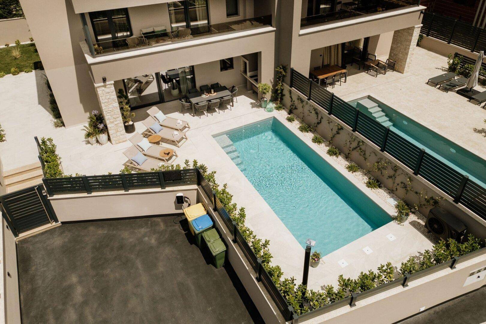 Vogelperspektive des Anwesens mit zwei Pools, Terrassen und umliegender Bepflanzung.