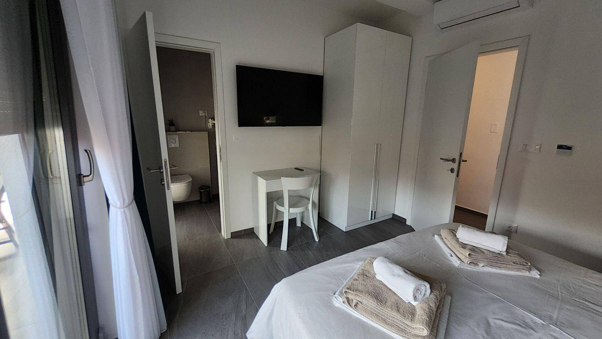 Schlafzimmer mit Zugang zu einem modernen Badezimmer und einem großen Kleiderschrank.