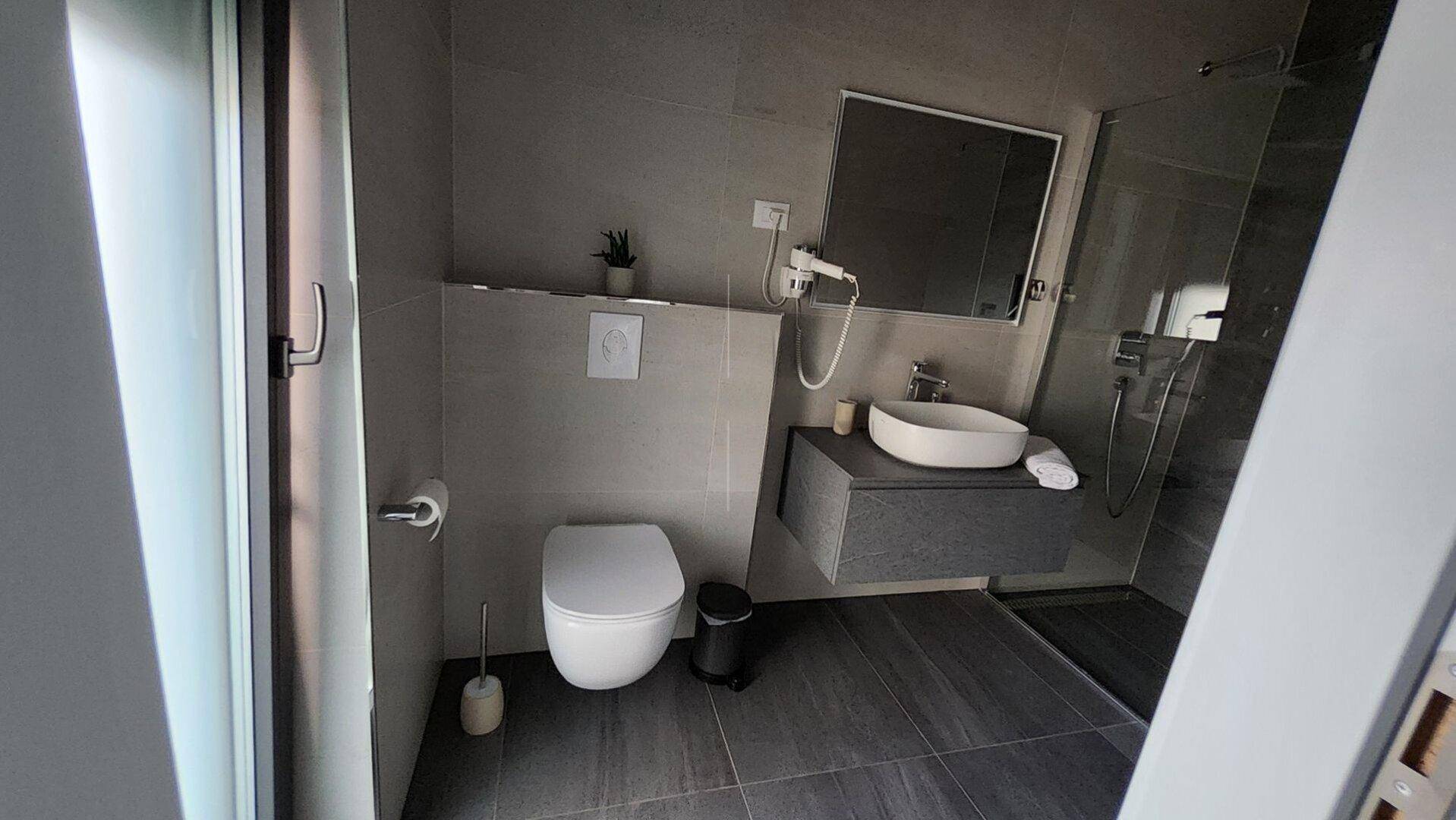 Modernes Badezimmer mit begehbarer Dusche, Hänge-WC und stilvollem Waschbecken.