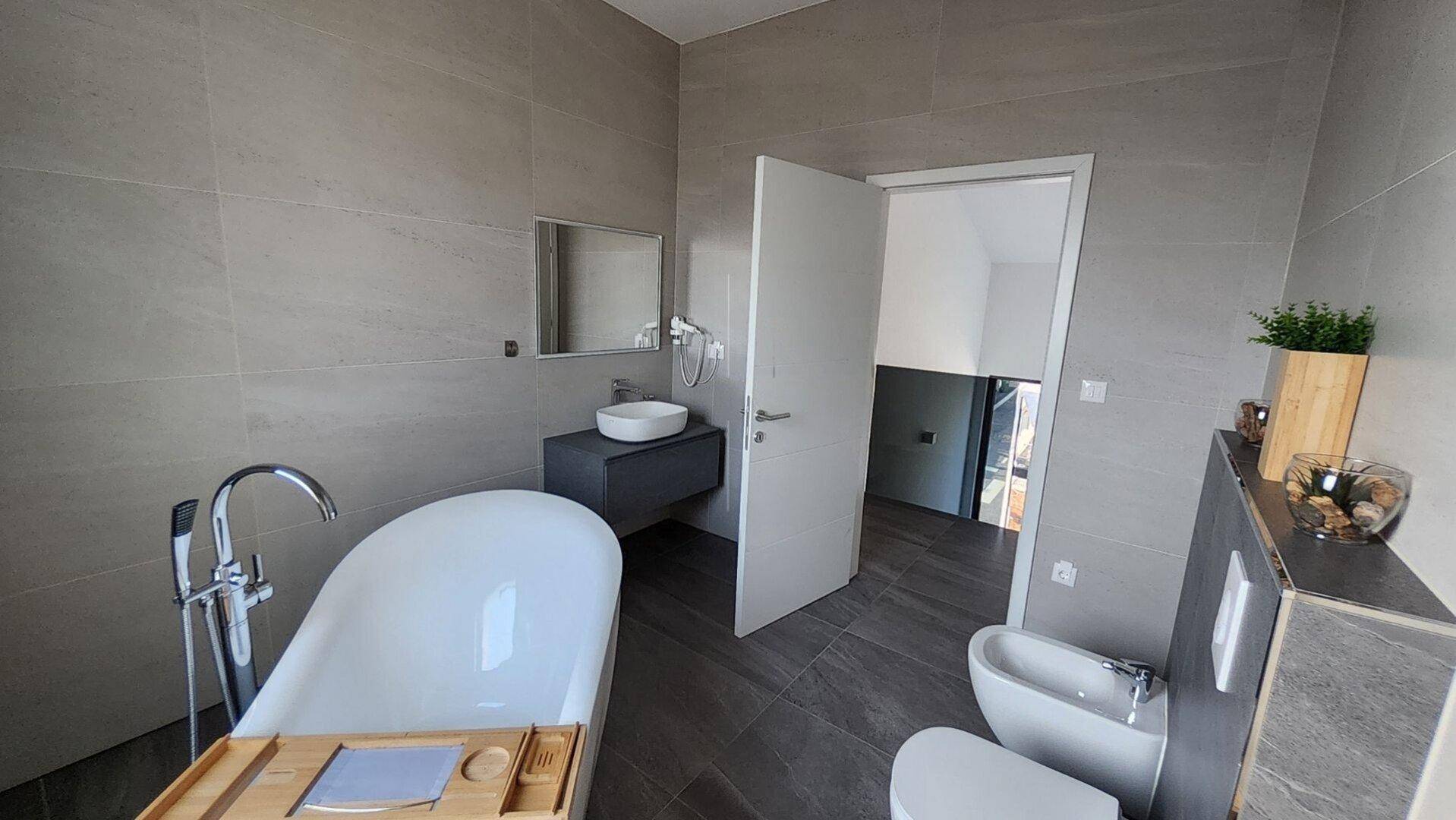 Geräumiges Badezimmer mit freistehender Badewanne, Bidet und modernem Waschtisch.