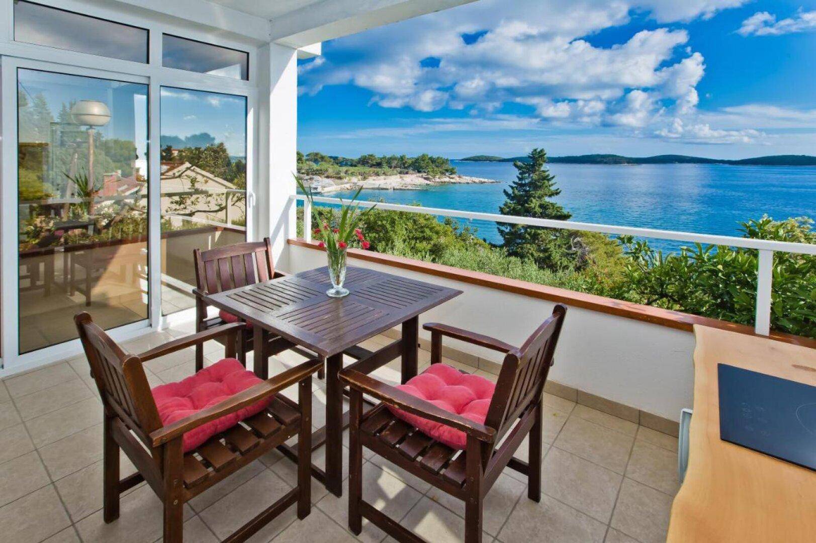 Heller Balkon mit Esstisch und atemberaubendem Blick auf das Meer und die Inseln.