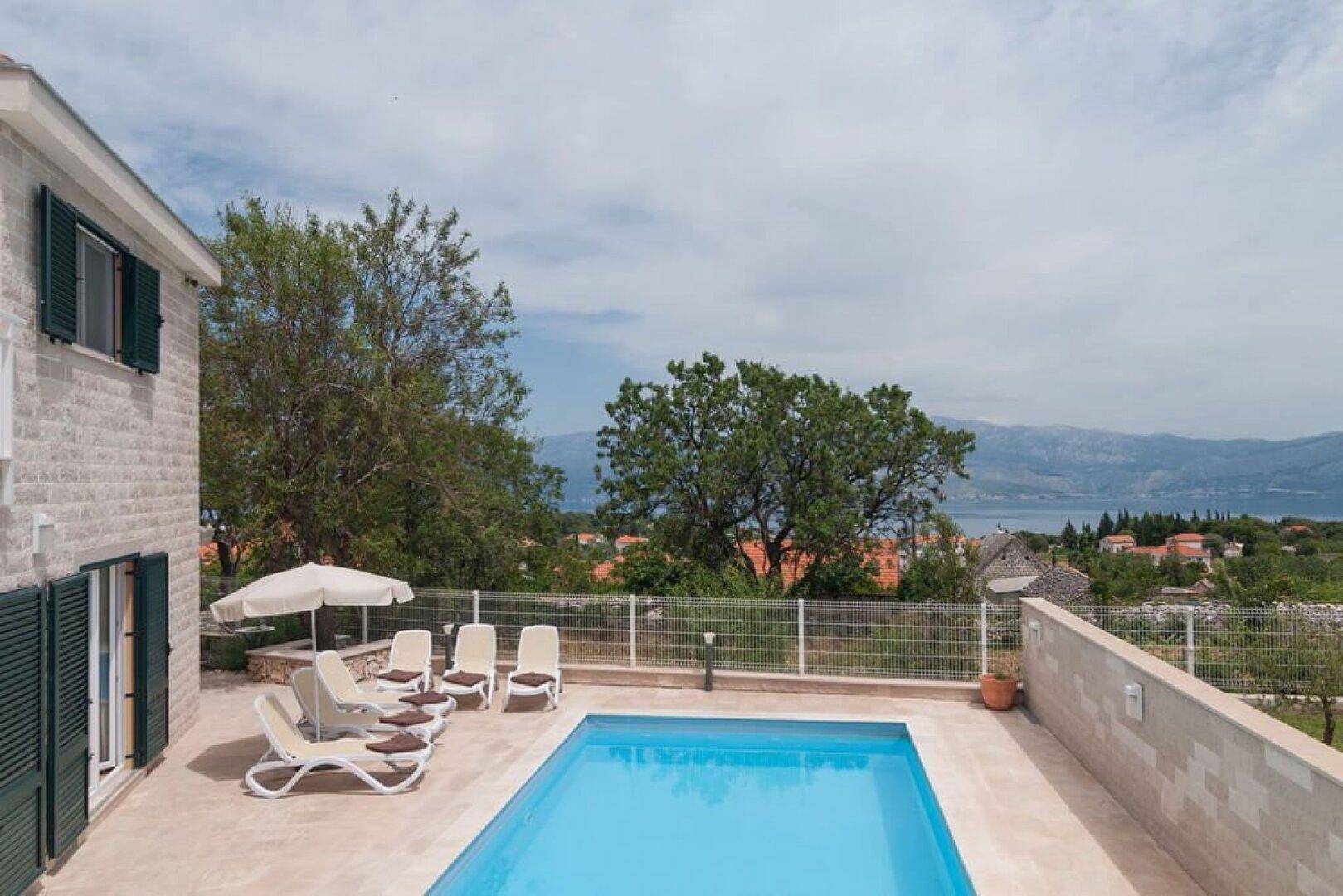 Panoramablick auf den Poolbereich der Villa mit weitreichender Aussicht auf die Landschaft und das Meer.