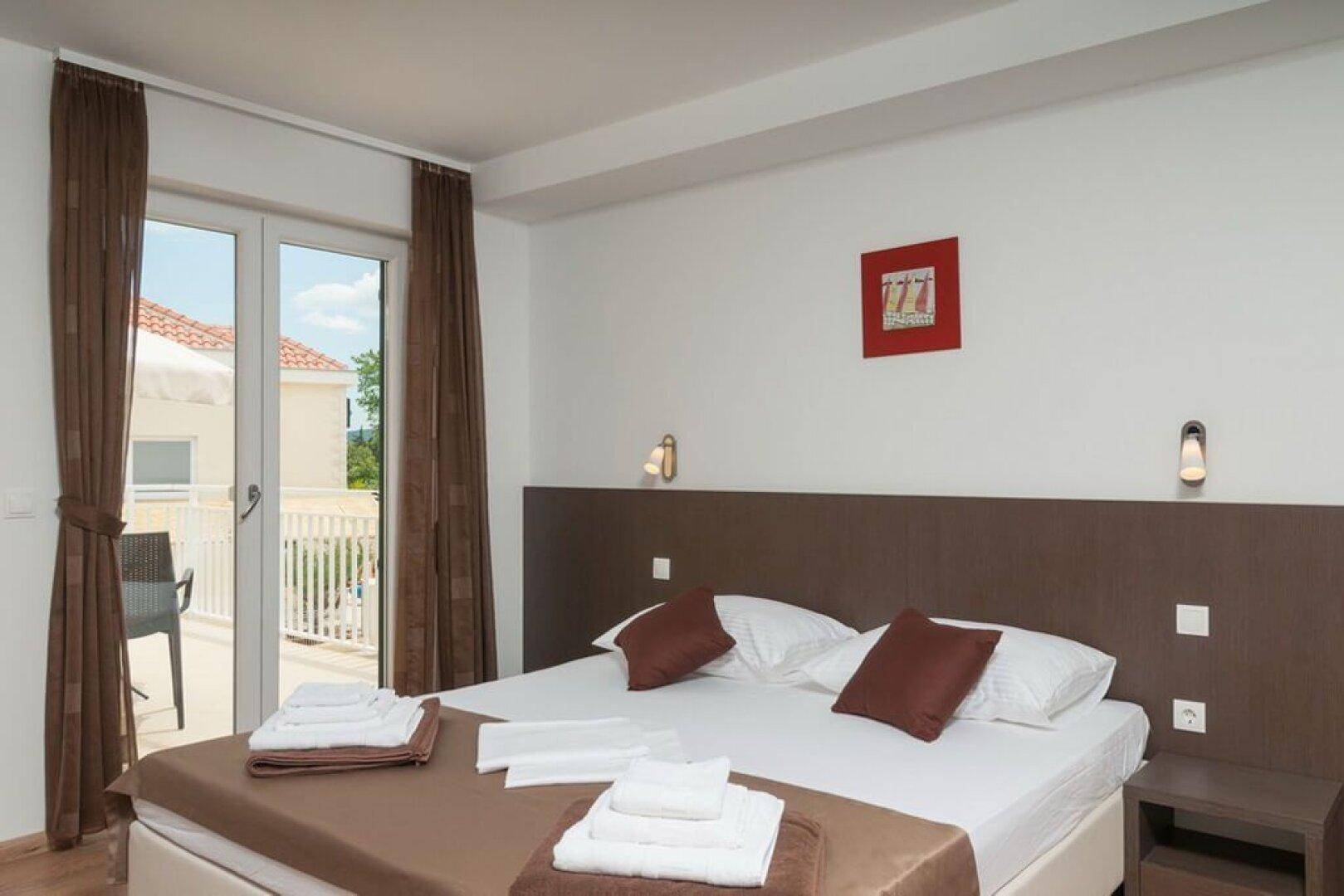 Schlafzimmer mit Doppelbett, Balkonzugang und Blick auf die Umgebung.