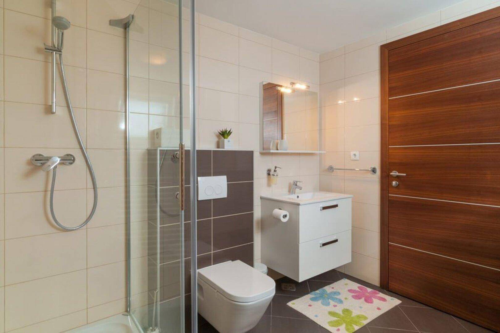 Modernes Badezimmer mit Dusche, wandhängendem WC und stilvollen Fliesen.