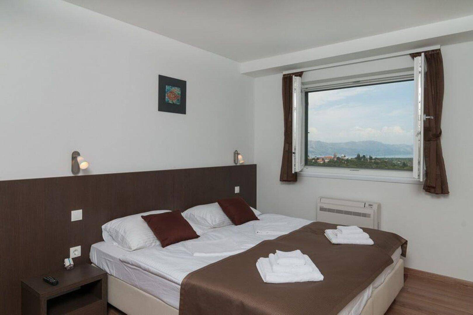 Schlafzimmer mit Doppelbett und Fenster, das einen weiten Blick auf die Landschaft bietet.
