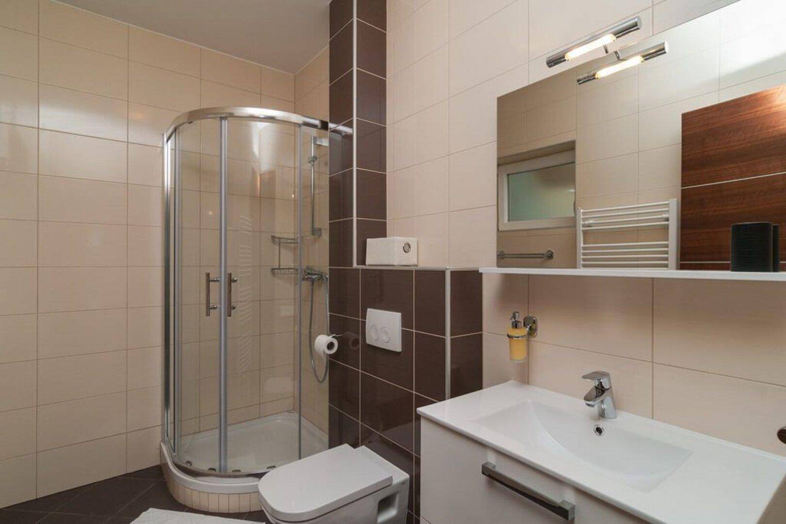 Badezimmer mit Duschkabine, Waschbecken und beheiztem Handtuchhalter.