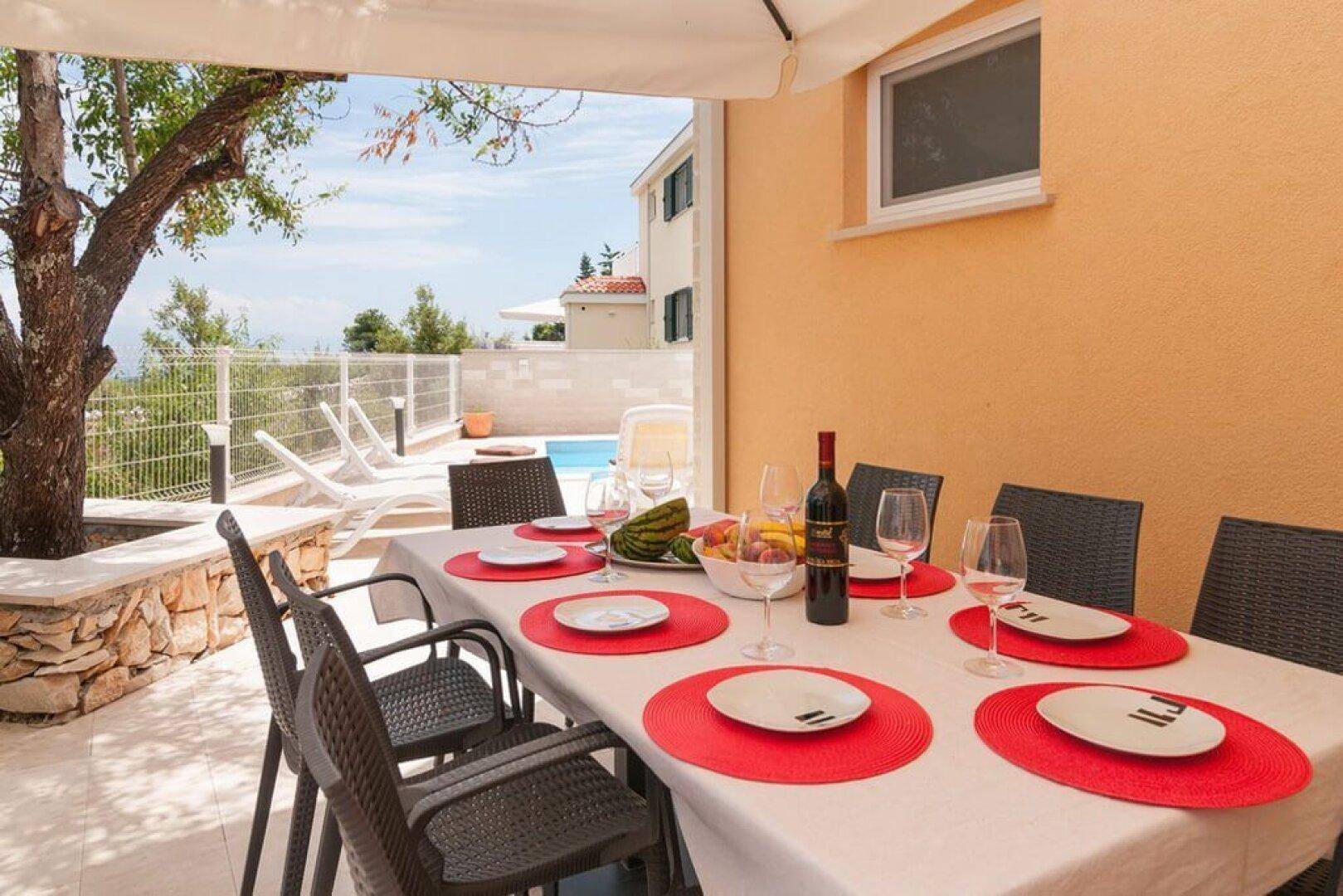 Große Essterrasse mit Tisch für sechs Personen und Blick auf den Poolbereich.