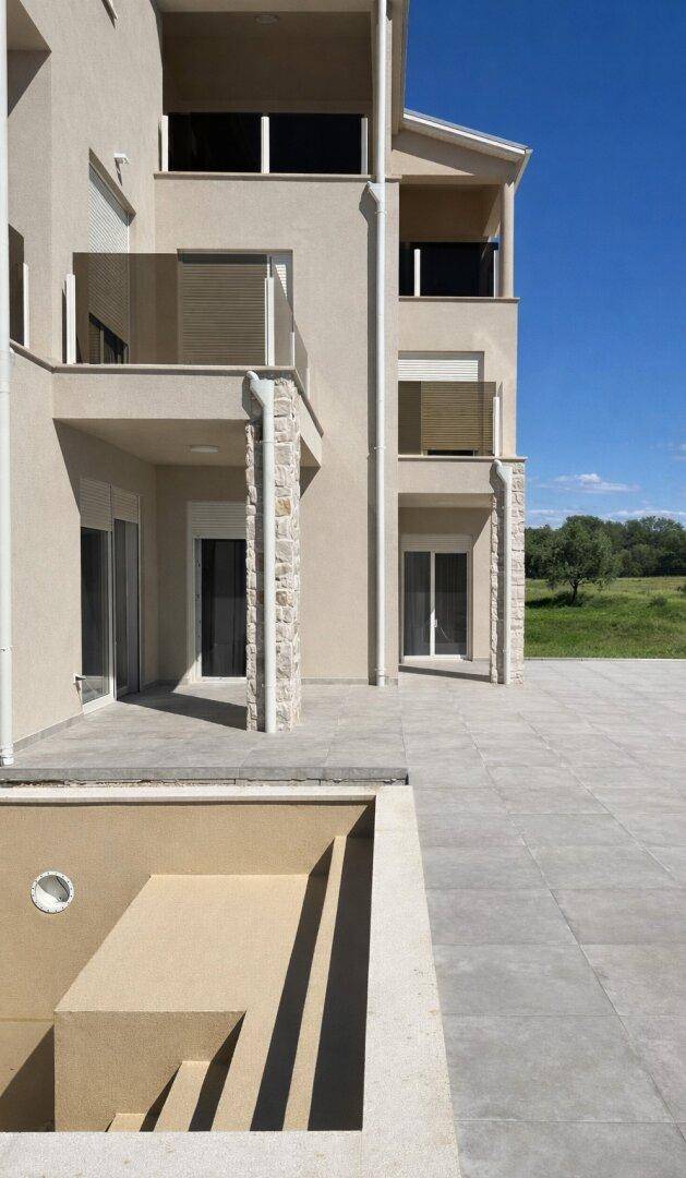 Außenbereich mit einem leeren Pool im Bau und einer gepflasterten Terrasse, bereit für die Fertigstellung.