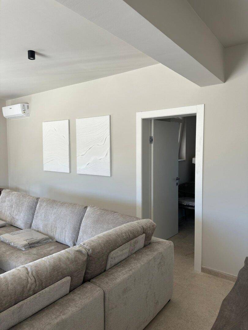 Gemütliche Ecke im Wohnzimmer mit einem großen grauen Sofa und installierter Klimaanlage.