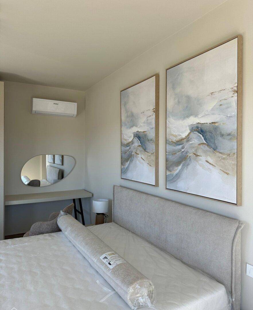 Modernes Schlafzimmer mit Klimaanlage, großem Bett und abstrakten Kunstwerken an der Wand.