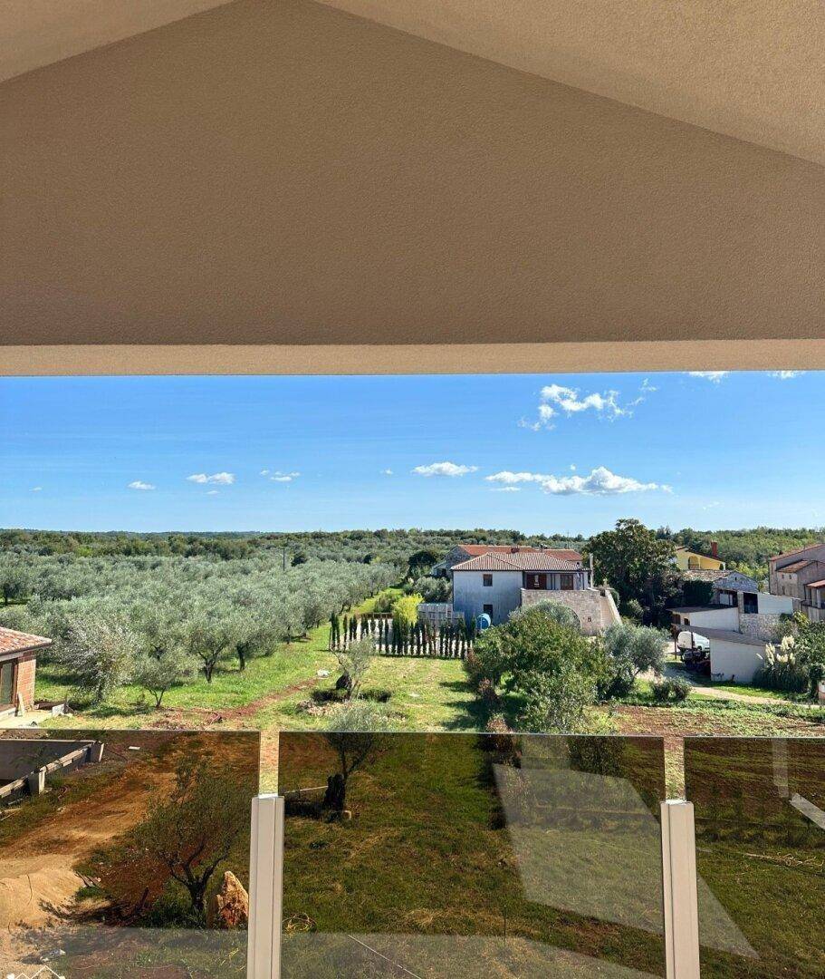 Weitläufiger Blick von einem Balkon über grüne Olivenhaine und die ländliche Umgebung.