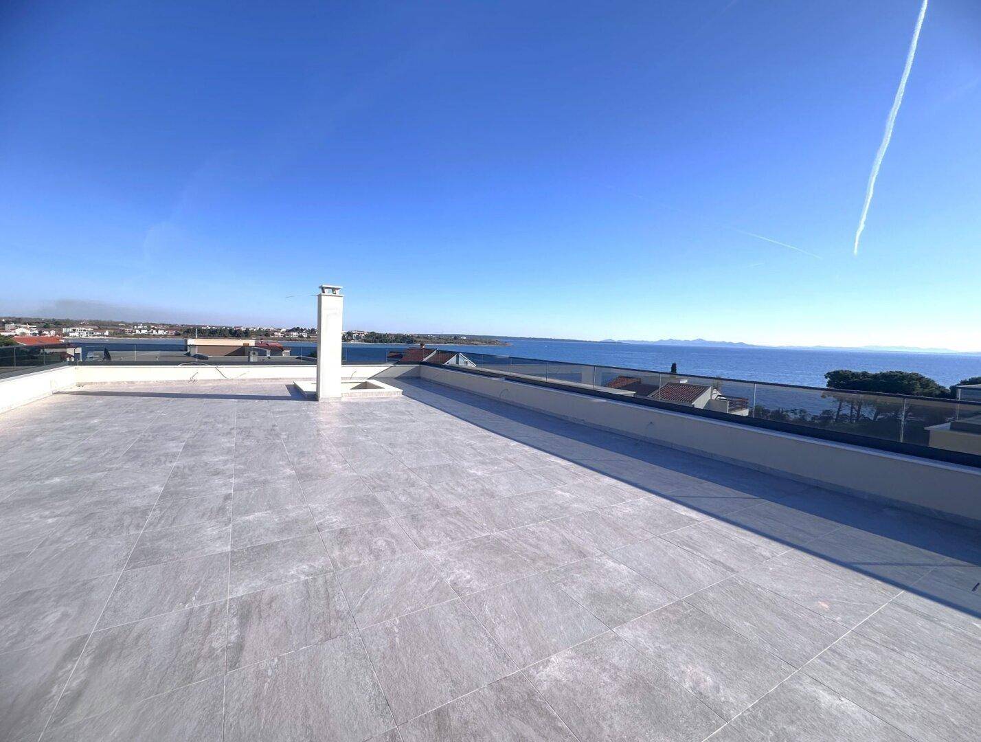 Weitläufige Dachterrasse mit Kamin und Panoramablick auf das Meer.